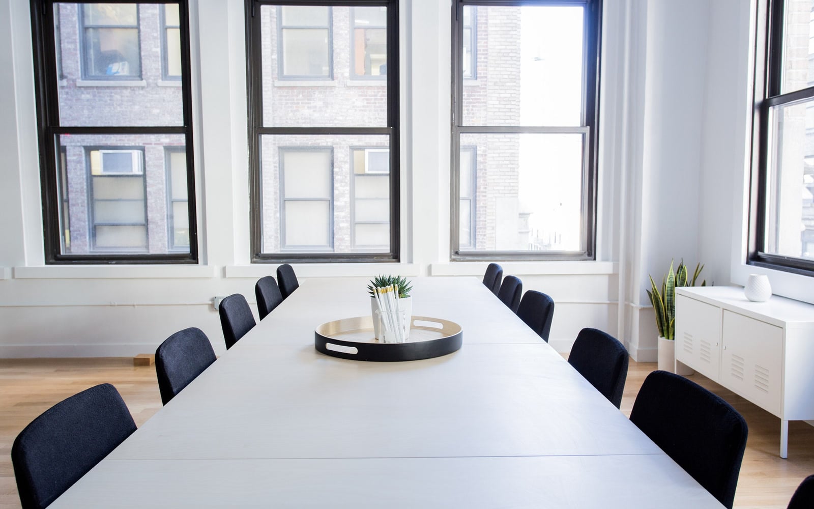 A meeting table surrounded by chairs in a bright room