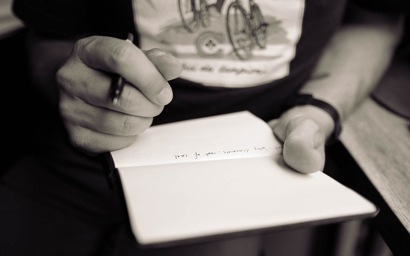 A person writes notes in an open notebook