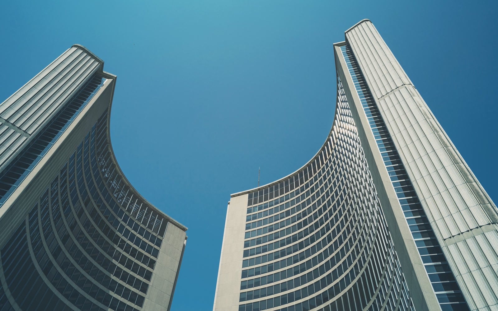 Curved Toronto City Hall towers against a blue sky