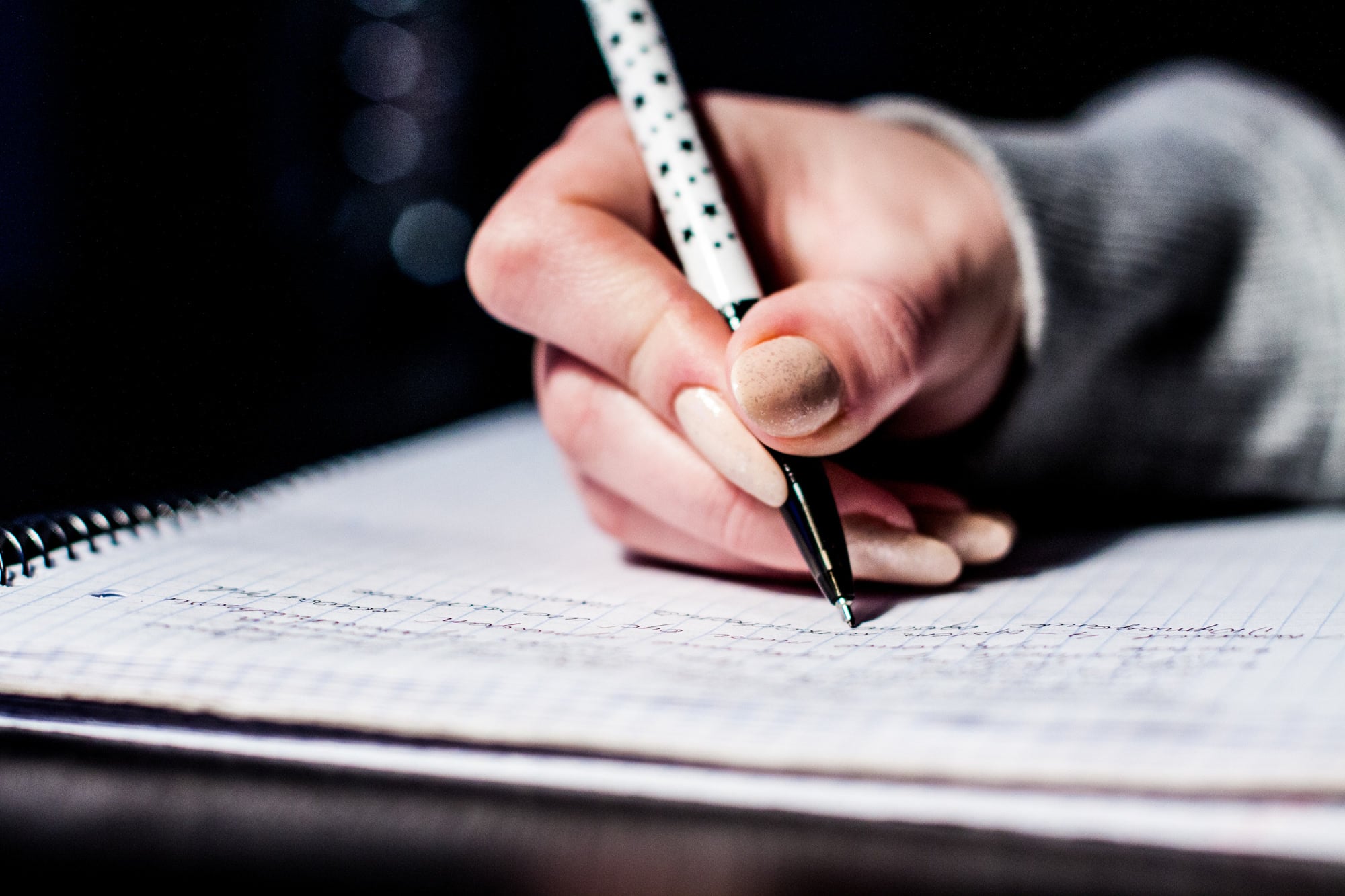 A hand writes notes in a lined notebook
